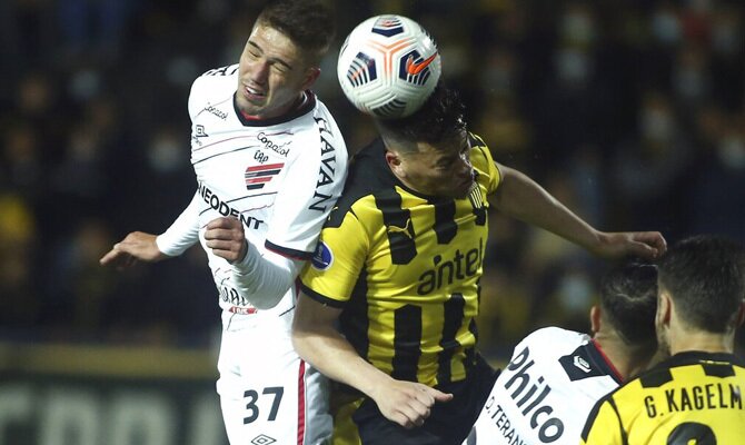 Bissoli y Rodríguez pelean por un balón aéreo. Cuotas y picks Athletico Paranaense vs Peñarol.