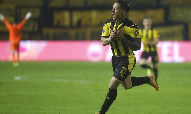 Imagen de un jugador de Peñarol agarrando su escudo. Picks y cuotas Peñarol vs Athletico-PR.