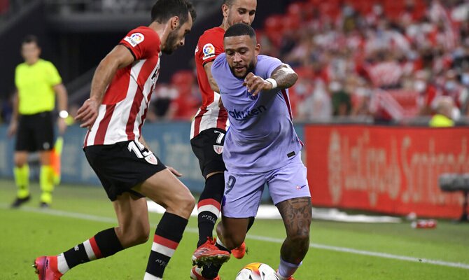 Memphis Depay trata de zafarse de dos defensas. Cuotas y picks Athletic de Bilbao vs Barcelona.