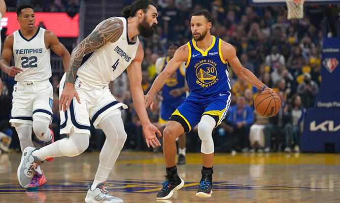 Steph Curry de los Warriors dribla ante la marca de Steven Adams de los Grizzlies