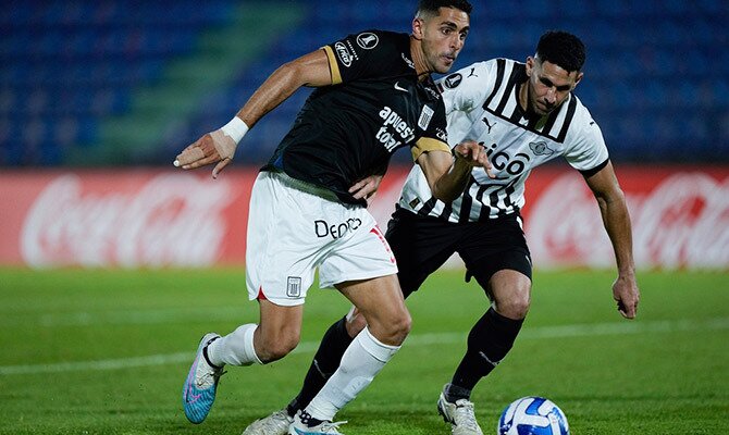Pablo Sabbag de Alianza Lima con el balón ante Alfio Oviedo de Libertad